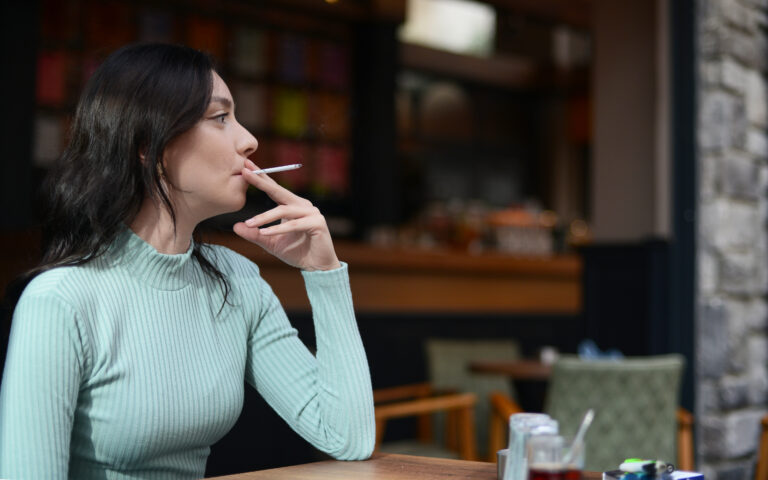 person seated at a table and smoking a cigarette