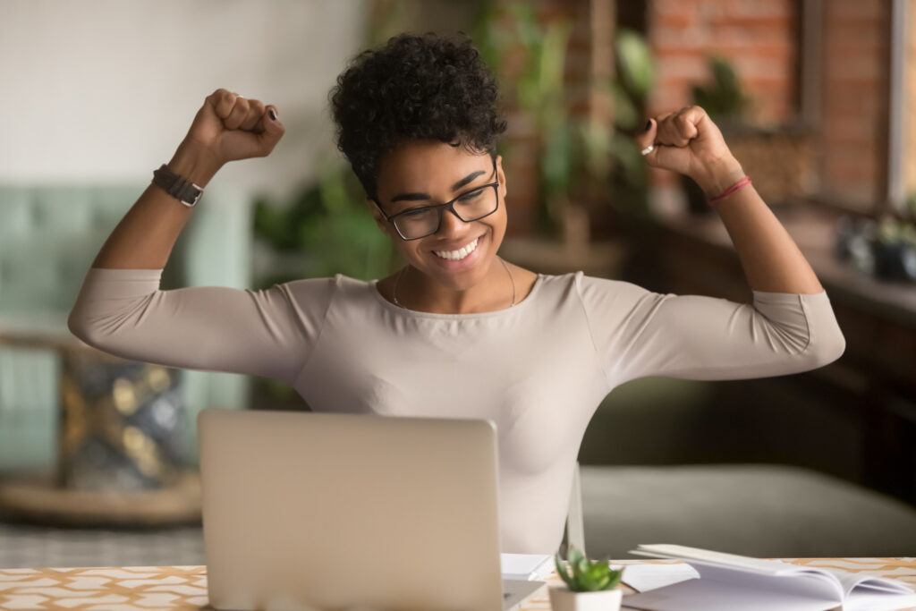 a woman raising her arms in triumph in front of a computer
