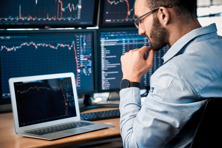 person gazing at a laptop located on a desk already supporting two pc monitors