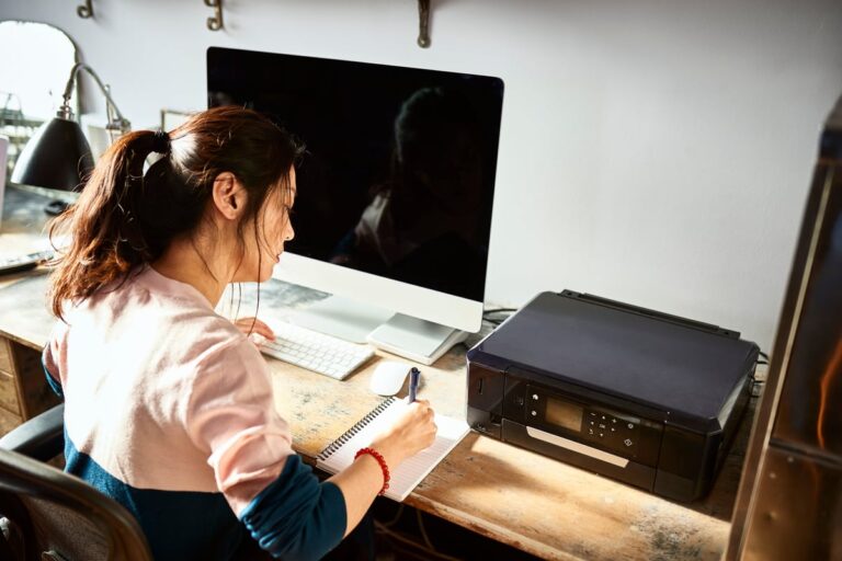 Woman writing in notebook at her home desk 4UKAi7d