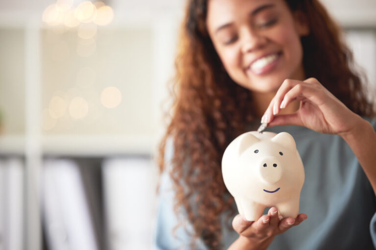 person stuffing money into a piggy bank and smiling