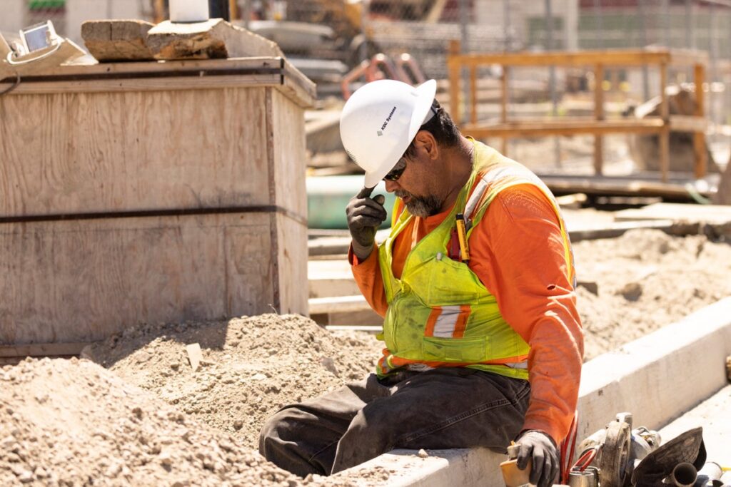 Worker adjusts his helmet on a construction site