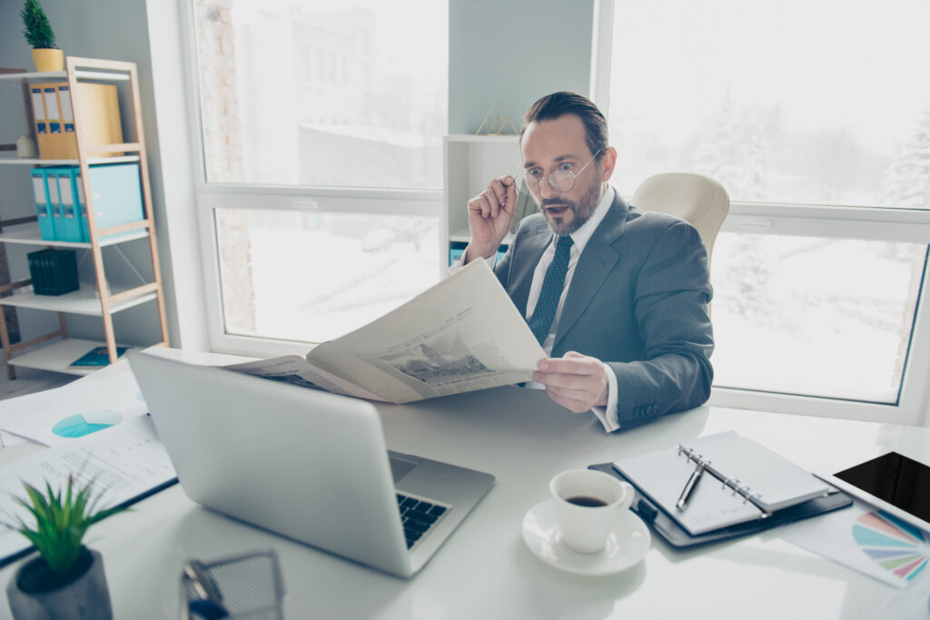 business person looks impressed while reading newspaper