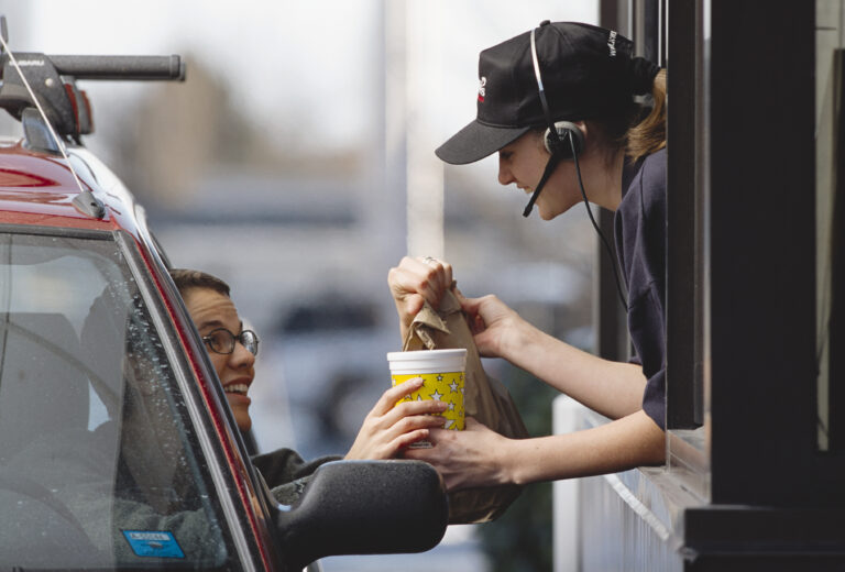 fast food worker delivering order out drive thru window