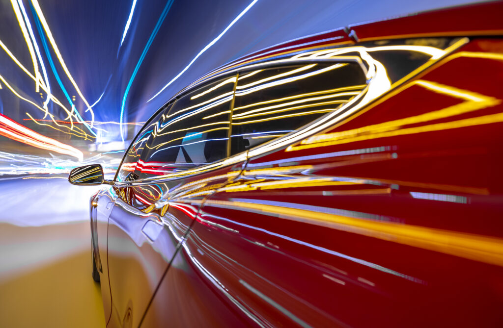 lights streak down a red tesla electric car racing down the highway