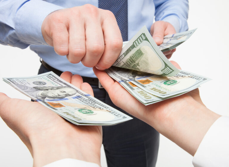 person placing money in both hands of another person