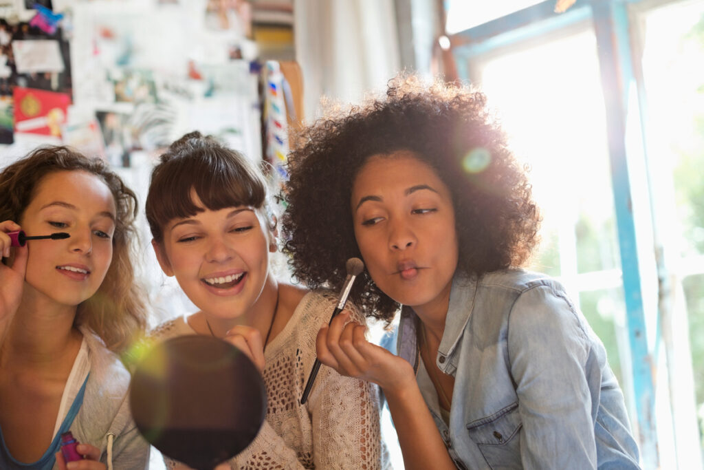 three people putting on makeup