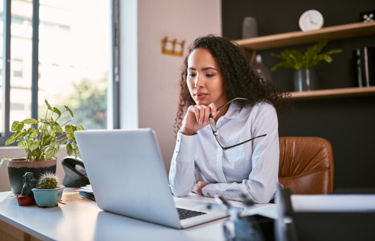 young investor thoughtfully holds glasses while looking at computer