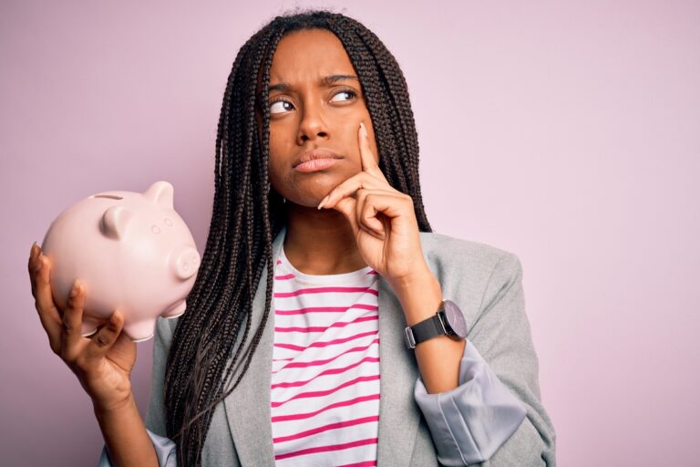 23 11 08 a person holding a piggy bank with a thinking or questioning expression on their face mf dload 1201x800 5b2df79