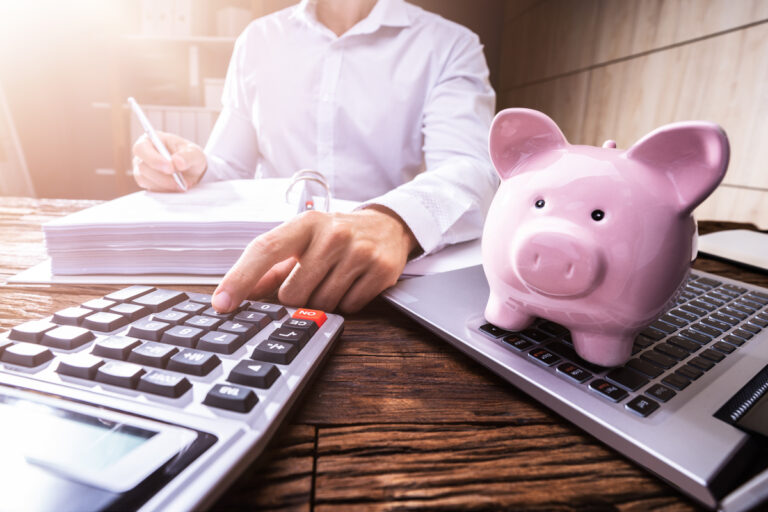 24 05 13 a person using a calculator with a piggy bank in the foreground mf dload 1200x800 5b2df79