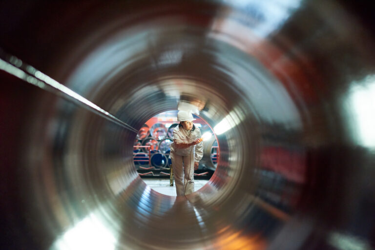 a person in a hard hat looking through an empty pipeline