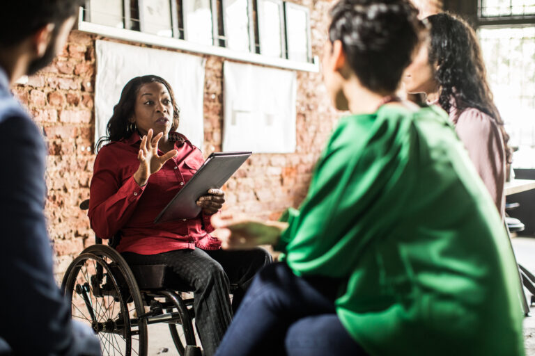 businessperson in wheelchair leading team meeting