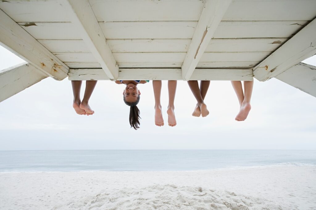 peoples legs sticking out from under a boardwalk with one face