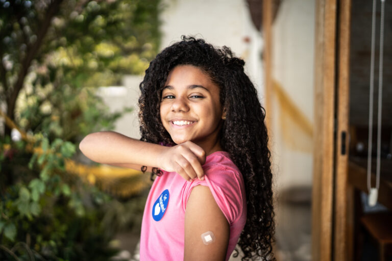 person smiling while showing off fresh vaccine shot