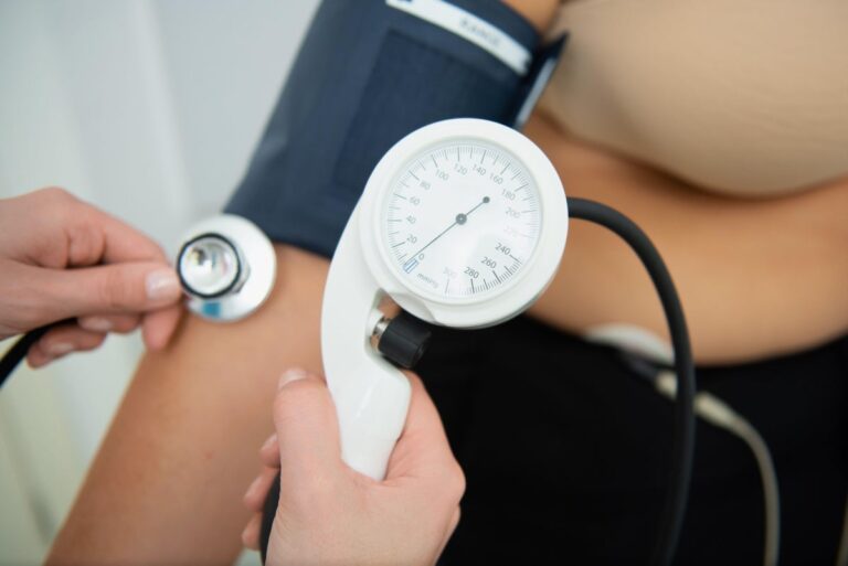 A healthcare professional administers a cardiology test with electrodes and blood pressure cuff