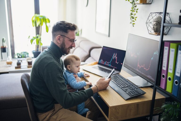 a father holds a baby while trading stocks