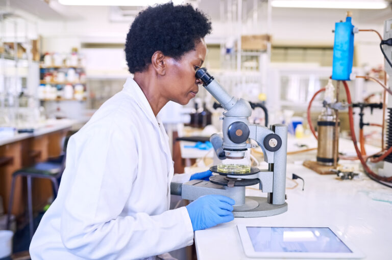 scientist peers into microscope in laboratory