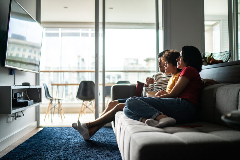 three people on couch watching tv living room