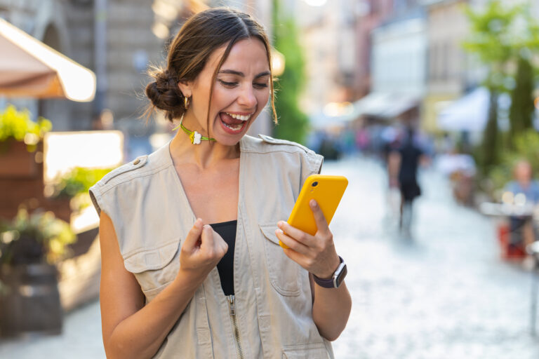 person reacting joyfully to something on a smartphone