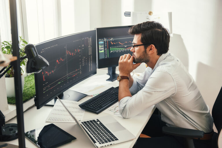 person sitting at a desk looking at two monitors