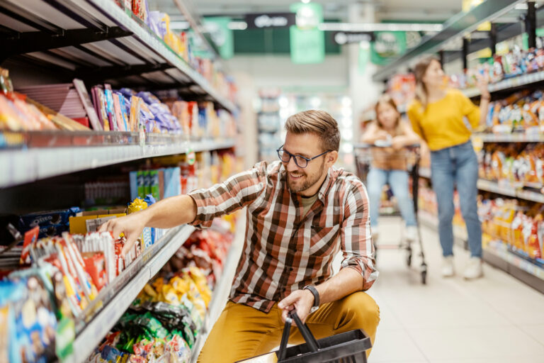 a person smiles while selecting a product off a shelf in a store