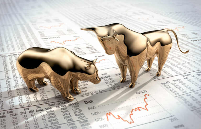 bull bear figures on top of stock data sheets