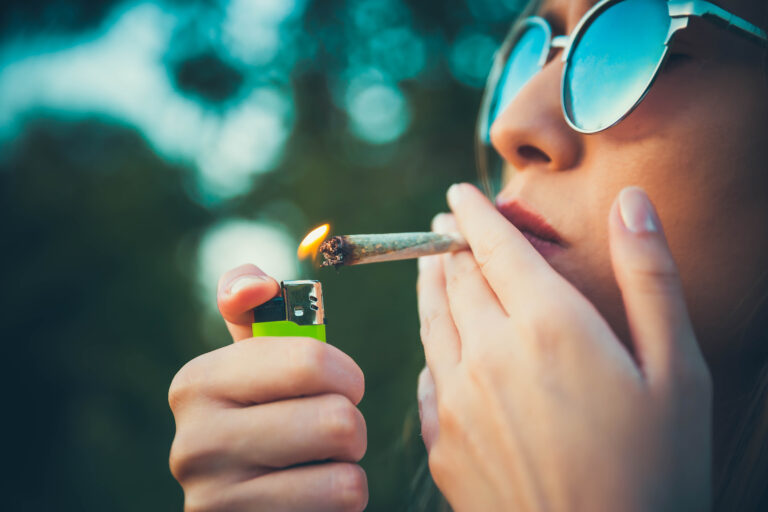 person lighting and consuming a marijuana cigarette
