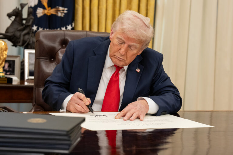 white house president donald trump signing executive order at resolute desk in oval office